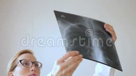 金发年轻的女医生看着一副X光眼镜视频的预览图