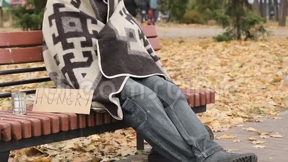饥肠辘辘无家可归冻僵的人坐在长凳上试图取暖贫穷视频的预览图
