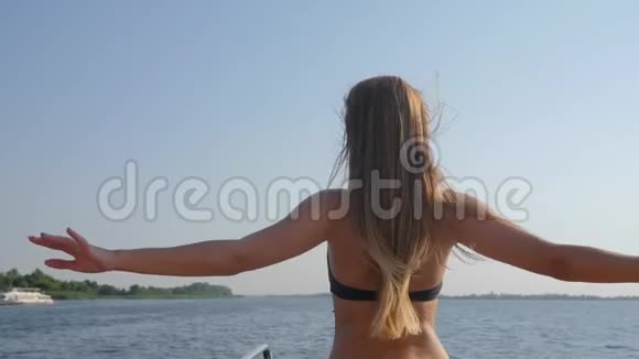 穿着泳衣的年轻女性在夏季享受自由和在海上举起双手奢华的头发在海上挥舞视频的预览图
