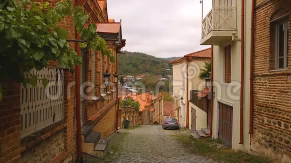 汽车和市民在狭窄的鹅卵石街道和舒适的房子在格鲁吉亚村视频的预览图