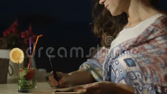 为美丽的女人写日记脸上带着微笑的特写镜头视频的预览图