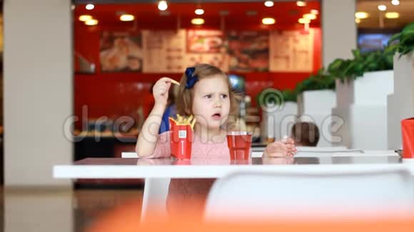 小女孩在咖啡馆里吃快餐薯条和喝果汁视频的预览图