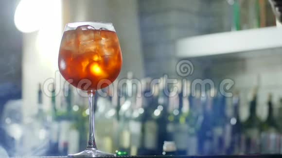 酒保在酒精饮料中加入柠檬片和塑料吸管在酒杯特写中加入冰块在没有聚焦的地方加入雾视频的预览图