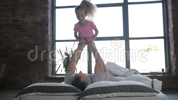 玩耍的父亲把女儿抱在家里的床上视频的预览图