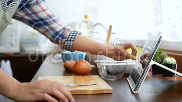 4K女人用手指在平板电脑上滑动切洋葱剥洋葱准备烹饪原料然后在网上烹饪视频视频的预览图