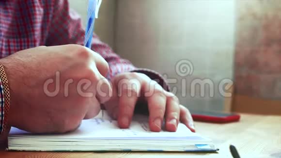 手在纸上写字年轻的商人坐在桌边喝咖啡做工作写在一本书里股票视频的预览图