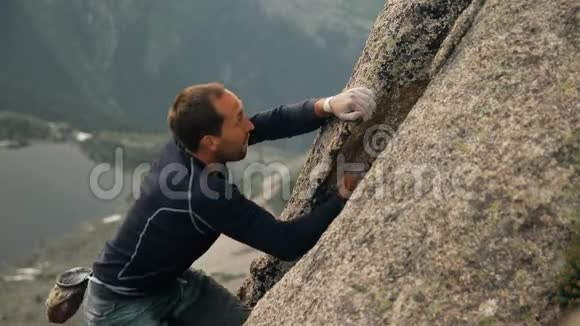 一个勇敢的年轻人在没有保险的情况下爬上高高的岩石视频的预览图