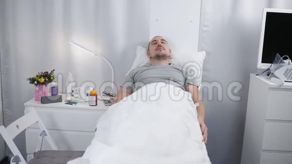 一个男人躺在医院房间的床上一个病人正睡在病房的床上视频的预览图