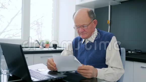 在线支付爷爷在网上工作手里拿着文件坐在桌上视频的预览图