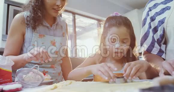 女孩学着和她的母亲和奶奶一起切饼干视频的预览图