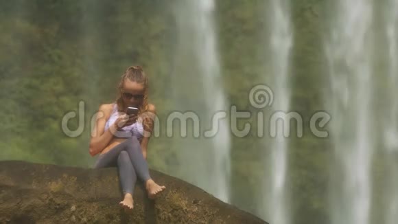 戴太阳镜的女孩短信反对瀑布视频的预览图