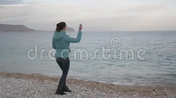 孤独寒冷海滩的女人高加索女人把石头扔进平静的大海视频的预览图