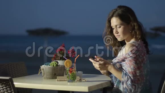 美丽的女人从触摸式电话海滨景色发送浪漫的信息视频的预览图