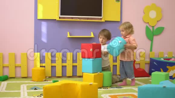 快乐的学龄前儿童在室内操场上玩柔软的多色积木儿童体育活动视频的预览图