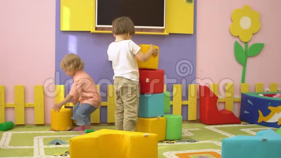 快乐可爱的学龄前儿童在室内操场玩多色软块儿童体育活动视频的预览图