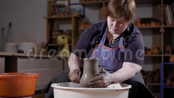 中年妇女用坐在黑暗手工作坊里的陶工轮制作陶瓷花瓶视频的预览图