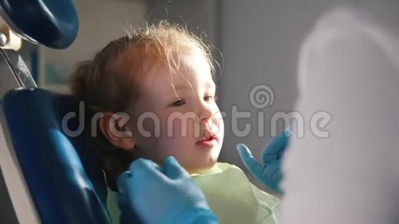 快乐的小女孩坐在牙科椅上口腔医生检查她的牙齿视频的预览图