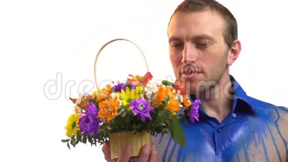 一个穿蓝色紧身衣的时髦男人嗅着一篮子花慢动作视频的预览图