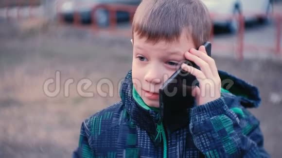 男孩在公园里用手机说话微笑着前景面部特写视频的预览图