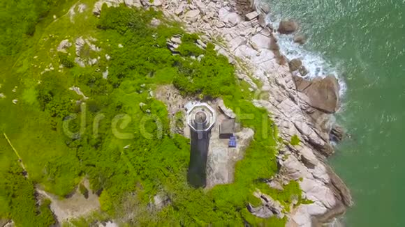 位于岩石岛上的海灯塔从飞行无人机俯瞰蓝色海景绿色海岸的空中景观灯房视频的预览图