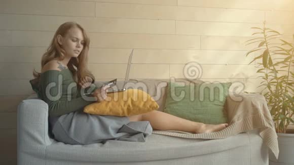 一位年轻漂亮的女士她用笔记本电脑拿着信用卡在家网上购物时面带微笑视频的预览图
