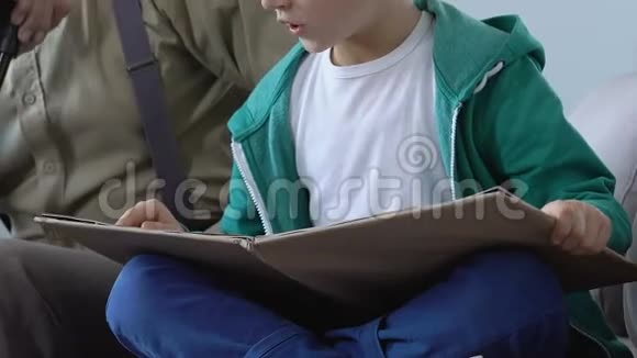 小男孩与爷爷坐在一起读书家人支持帮助视频的预览图