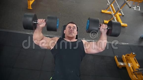 强壮的肌肉男在健身房做哑铃运动视频的预览图