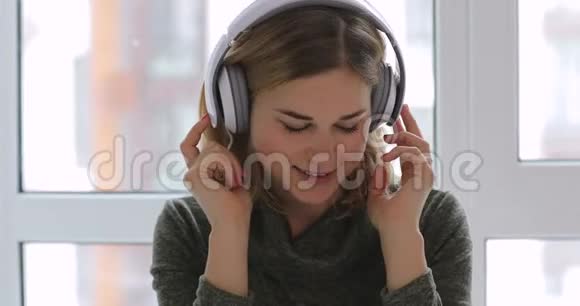 女人在家放松听着耳机里美妙的音乐视频的预览图
