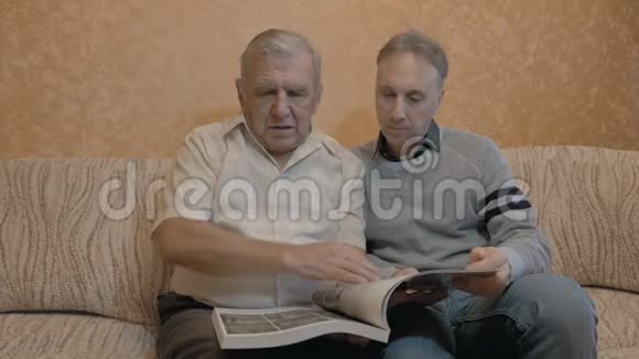 一位老人正在和他的成年儿子看一本书视频的预览图