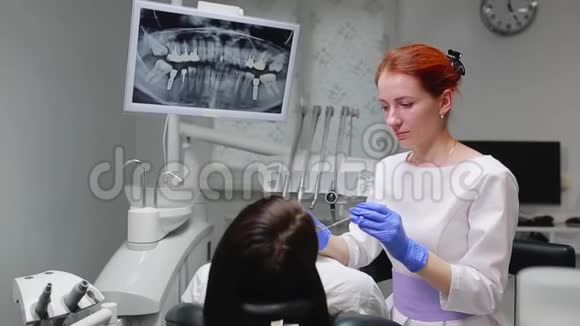 戴着蓝色手套和白色外套的女医生走近病人的椅子用X光和仪器视频的预览图