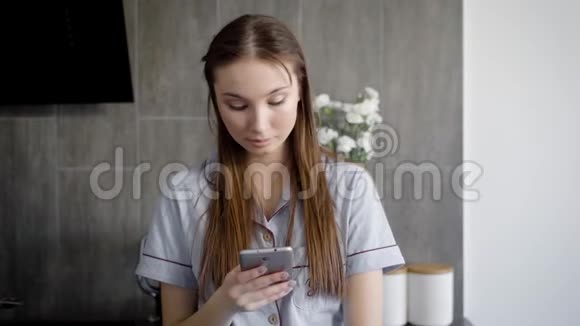 平静的年轻女子正在手机触摸屏上打字白天站在屋子里视频的预览图