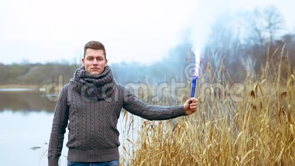 举着一支冒烟的火炬在湖边的英俊男子的照片视频的预览图