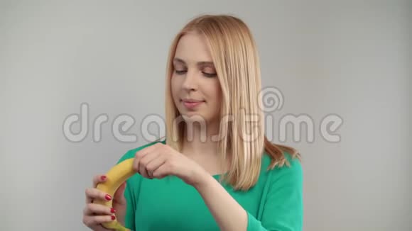 接近金发女人吃香蕉金发女孩咬成熟水果的肖像视频的预览图