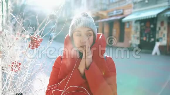 穿着红色冬衣的女孩试图温暖自己站在白雪覆盖的街道上视频的预览图