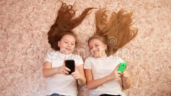 两个十几岁的女孩躺在地板上用这些小玩意打字视频的预览图