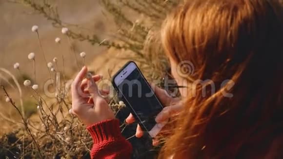金吉尔女摄影师用智能手机拍摄岩石海岸的花朵视频的预览图