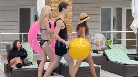 在昂贵的度假胜地穿着带充气戒指的泳衣的青年朋友在暑假陪伴视频的预览图