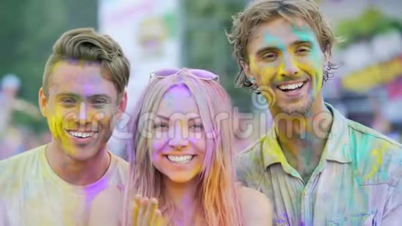 欢乐的年轻人微笑着对着镜头拍手上沾满了彩色粉末视频的预览图