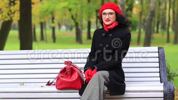 秋天公园里带着红色袋子的女人视频的预览图