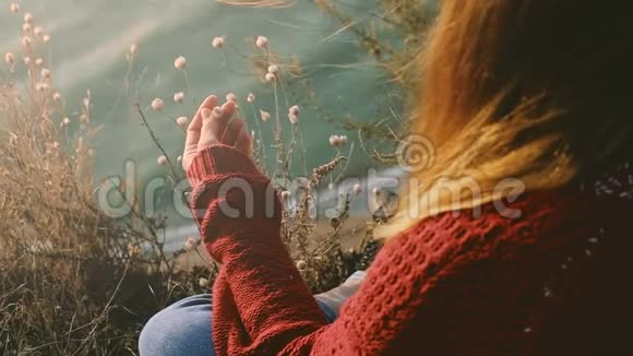 年轻冷静的姜姑娘穿着红色毛衣在岩石海岸边眺望大海视频的预览图