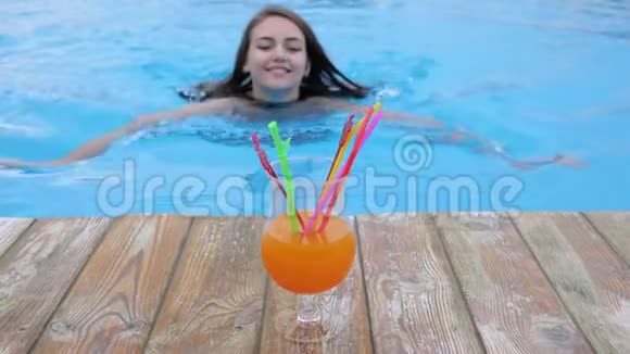 穿着泳衣的漂亮女孩在游泳池游泳喝鸡尾酒视频的预览图