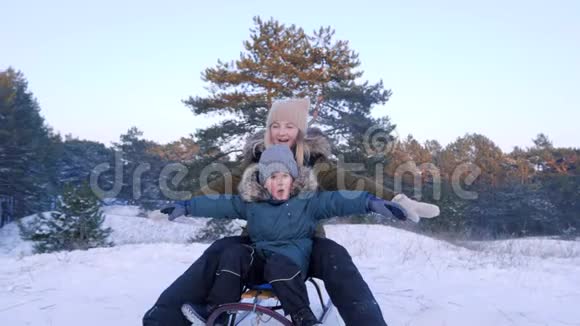 母亲和儿子在雪地上玩着玩他们的手臂举在森林里视频的预览图