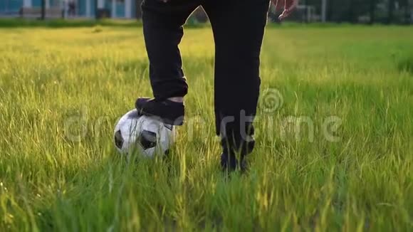可爱的男孩在公园的夕阳下用足球踢足球s视频的预览图