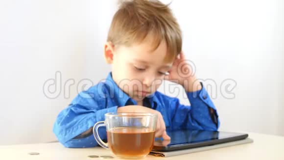 孩子在玩平板桌子上有一杯茶镜头的焦点对准了茶视频的预览图