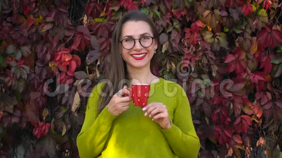 带眼镜的女人在温暖的秋日在户外喝茶或咖啡咖啡时间视频的预览图