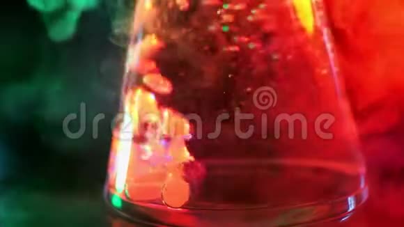 液体在霓虹灯色光下在烧瓶中沸腾与水中的干冰进行漂亮的化学反应的概念视频的预览图