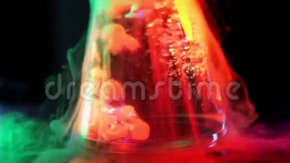 与水中的干冰进行漂亮的化学反应液体在霓虹灯色光下在烧瓶中沸腾的概念视频的预览图