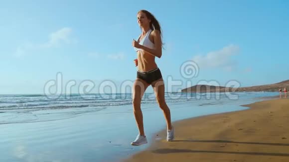 美丽的运动女性沿着美丽的沙滩奔跑健康的生活方式在附近享受活跃的暑假视频的预览图