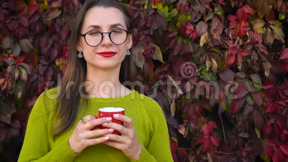 带眼镜的女人在温暖的秋日在户外喝茶或咖啡咖啡时间视频的预览图