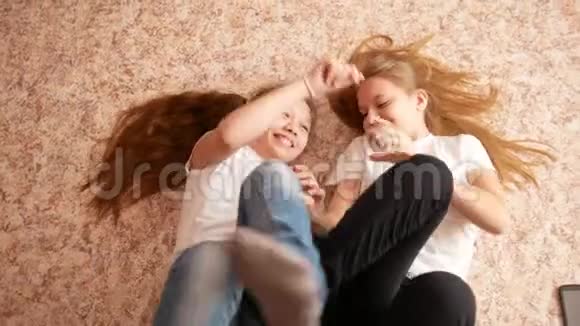 两个十几岁的女孩躺在地板上玩玩得开心视频的预览图